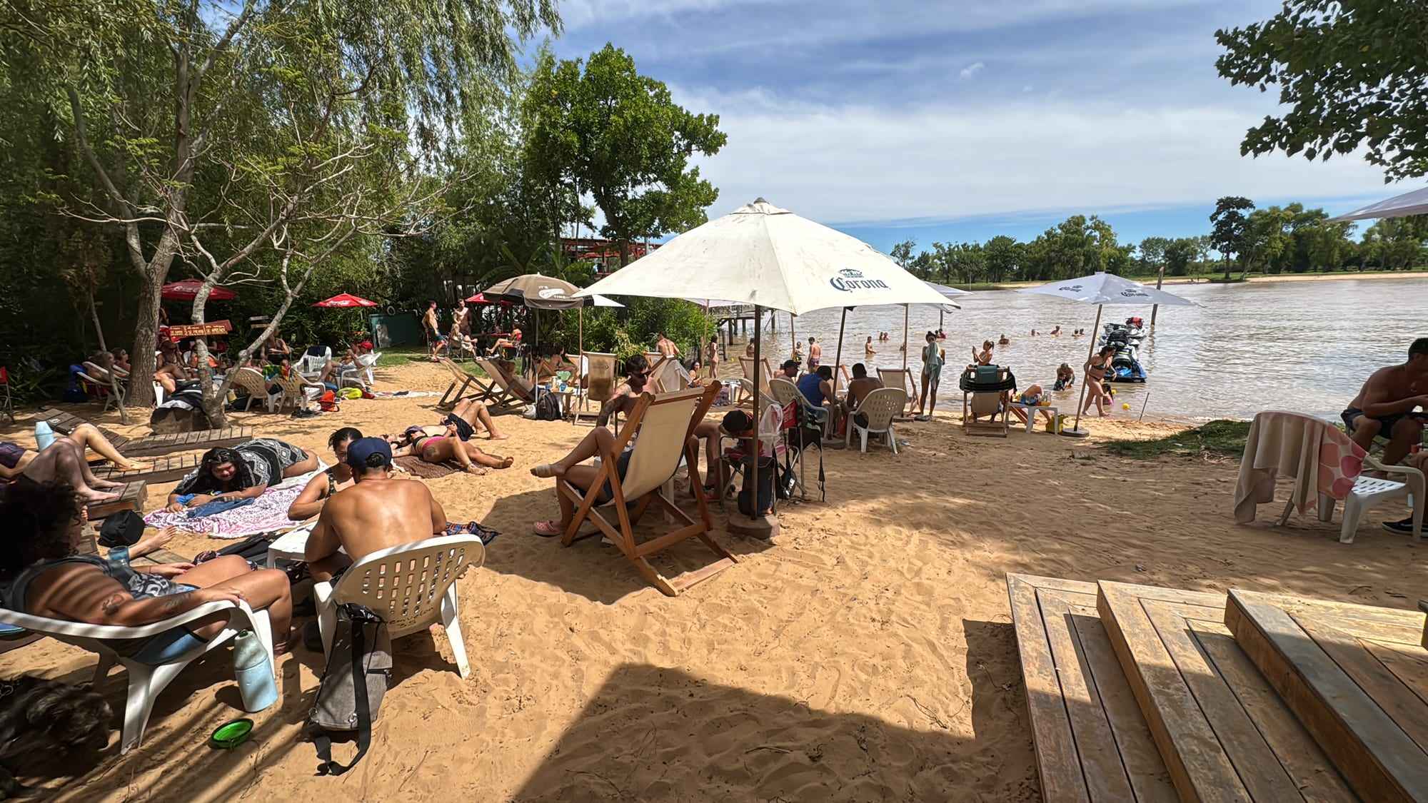 La playa un día de verano, con gente tomando sol frente al río.